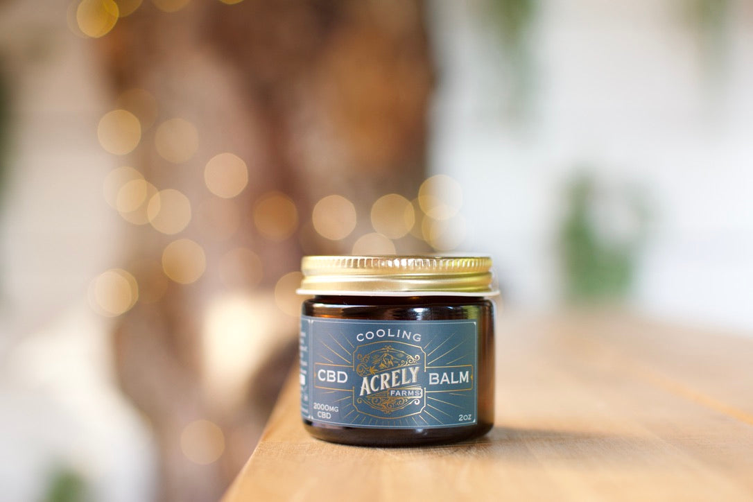 Jar of Acrely CBD Balm on a wooden surface with a blurred background