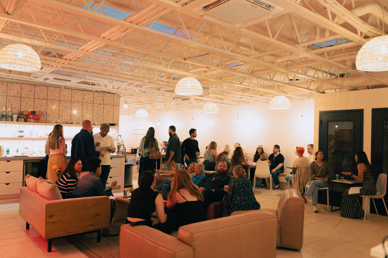 People socializing in a modern office space with beige sofas and white walls.