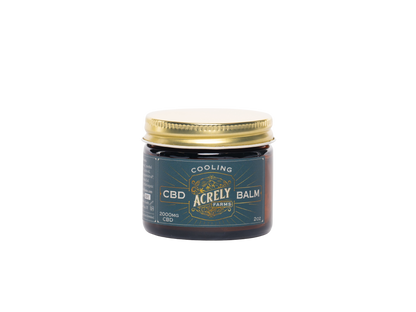 A small amber glass jar of Acrely Farms Cooling CBD Balm with a gold metal lid and a dark teal label, centered on a plain white background.