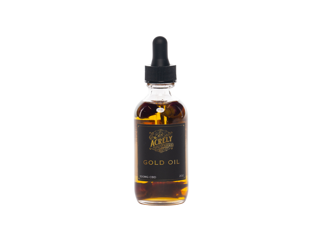 A clear glass dropper bottle filled with amber-gold liquid, featuring a black label with gold lettering that reads &