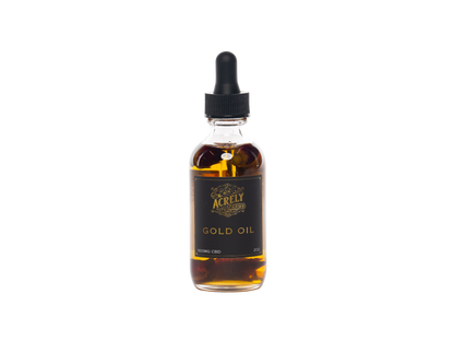 A clear glass dropper bottle filled with amber-gold liquid, featuring a black label with gold lettering that reads &