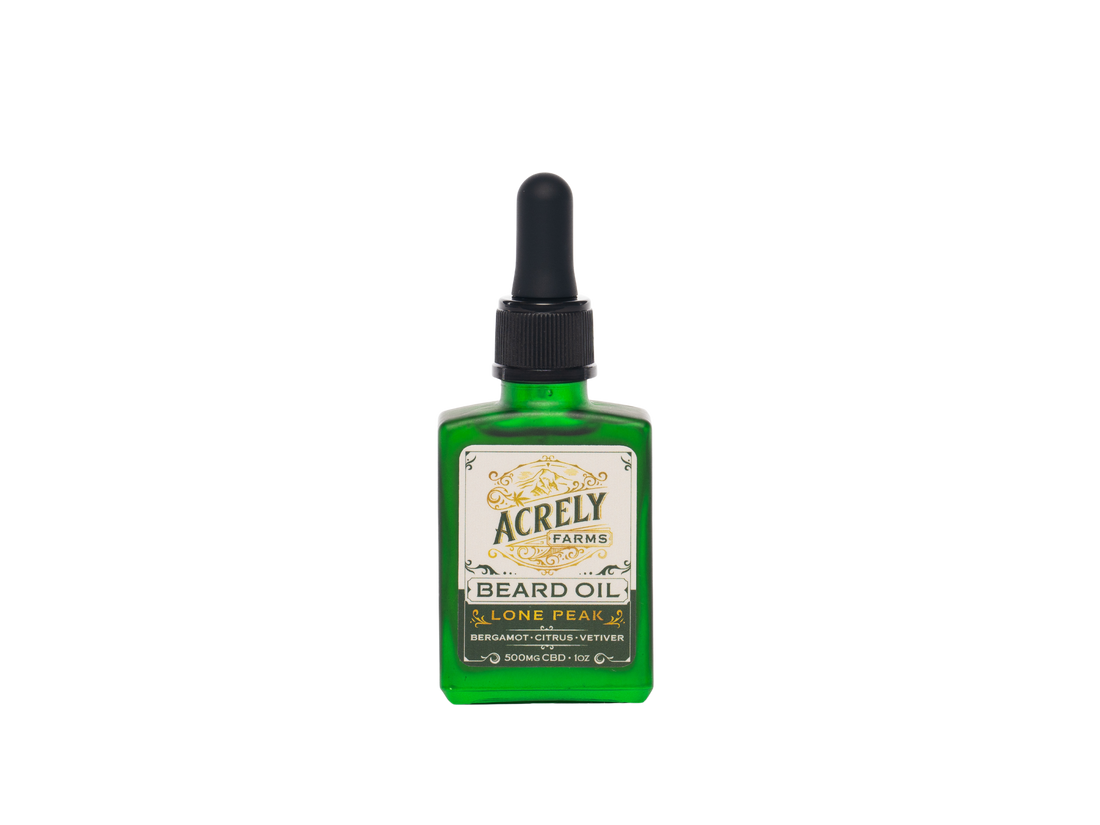 A green glass bottle of Acrely Farms Lone Peak Beard Oil with a black dropper cap and a cream-colored label, centered on a plain white background.