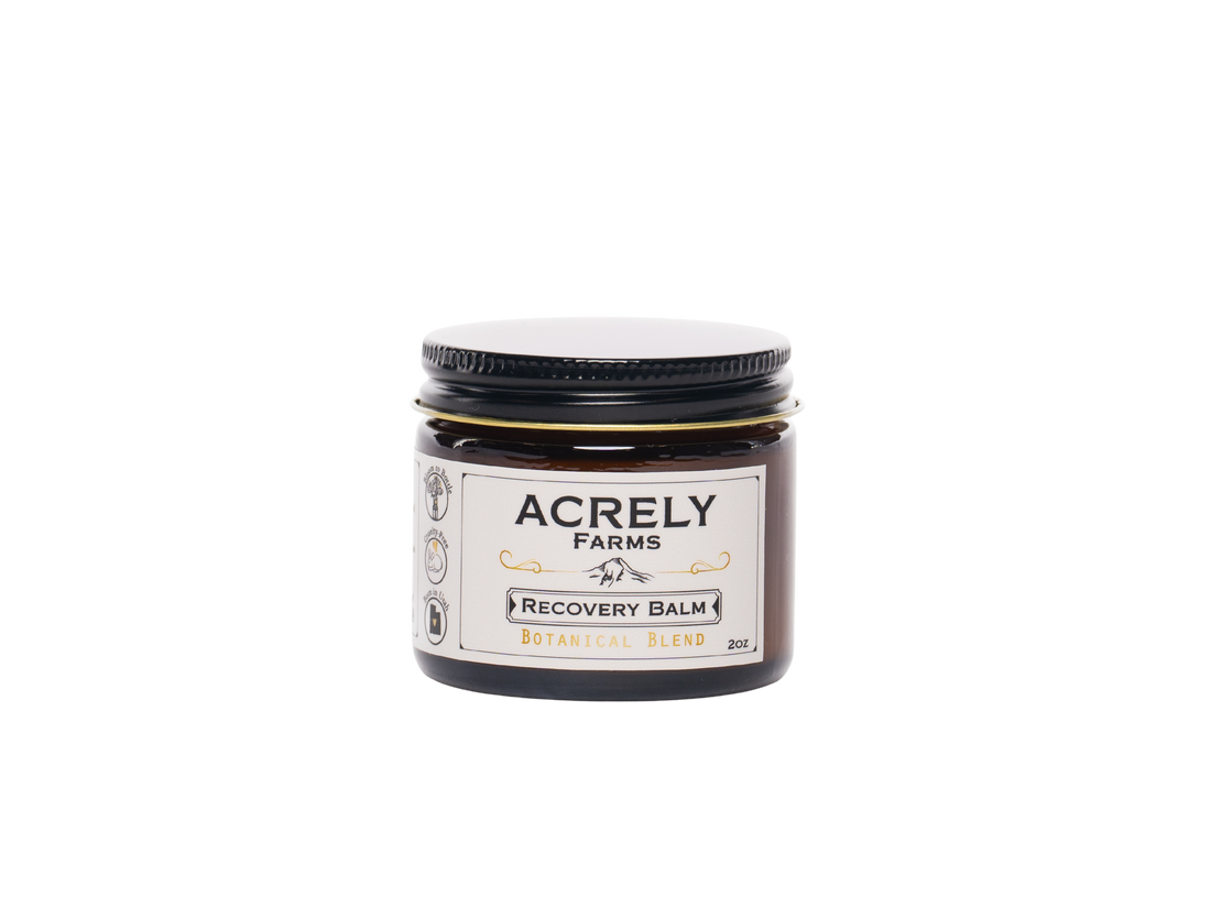 A small amber glass jar of Acrely Farms Recovery Balm with a black lid and a cream-colored label, set against a plain white background.