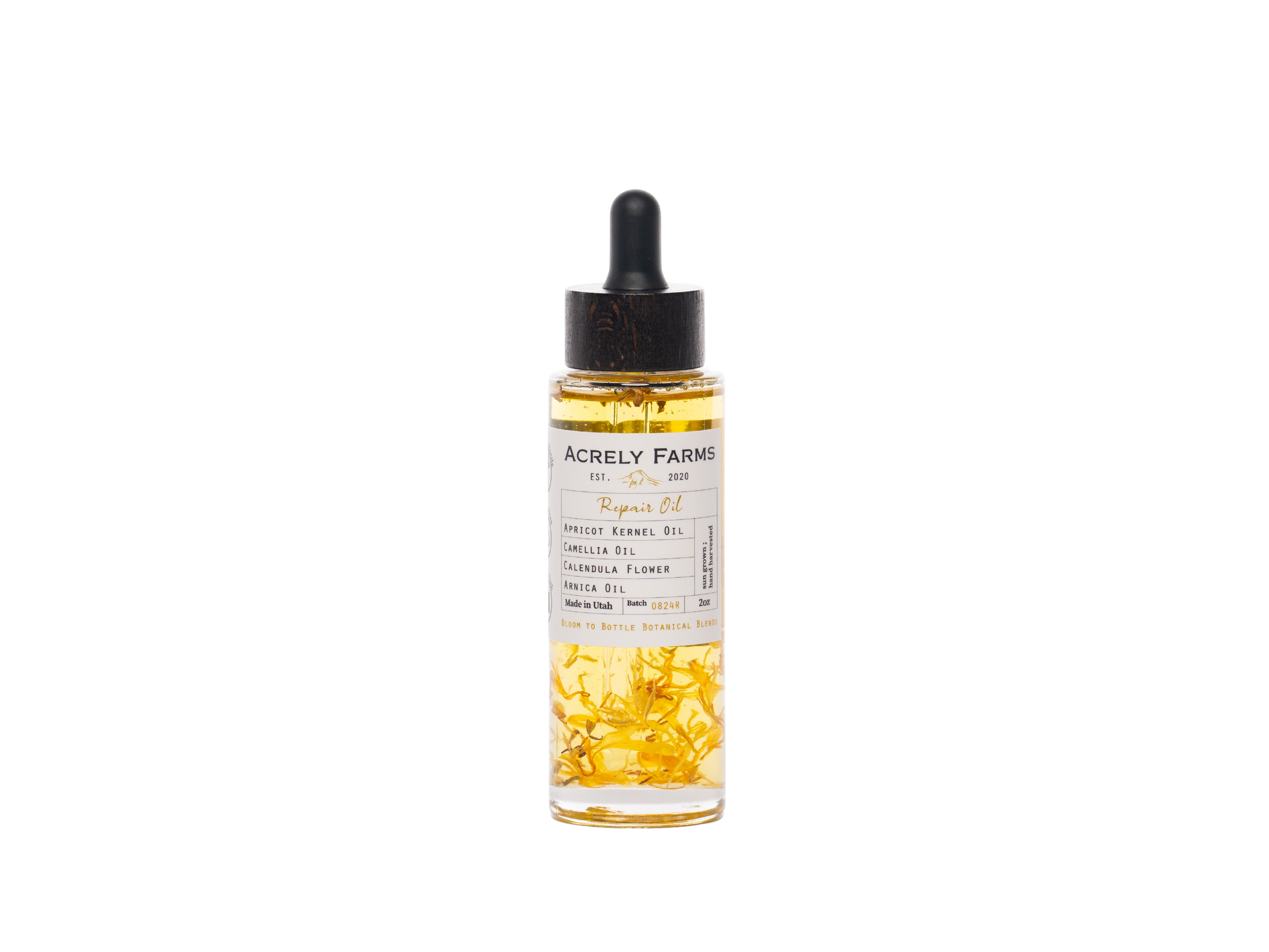 A clear glass dropper bottle of Acrely Farms Repair Oil with a black rubber dropper cap, filled with golden-yellow oil and containing visible dried yellow flower petals, set against a plain white background.